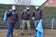 Foto: Nick, Freddy & Fabian Teammitglieder des Stadtjugendring Schneverdingen beim Müllsammeln. Nick, Freddy und Fabian tragen Müllsäcke und Greifer.
